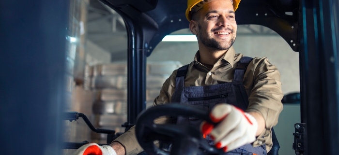 A man in a hardhat operating forklift machine in warehouse in Toledo, OH